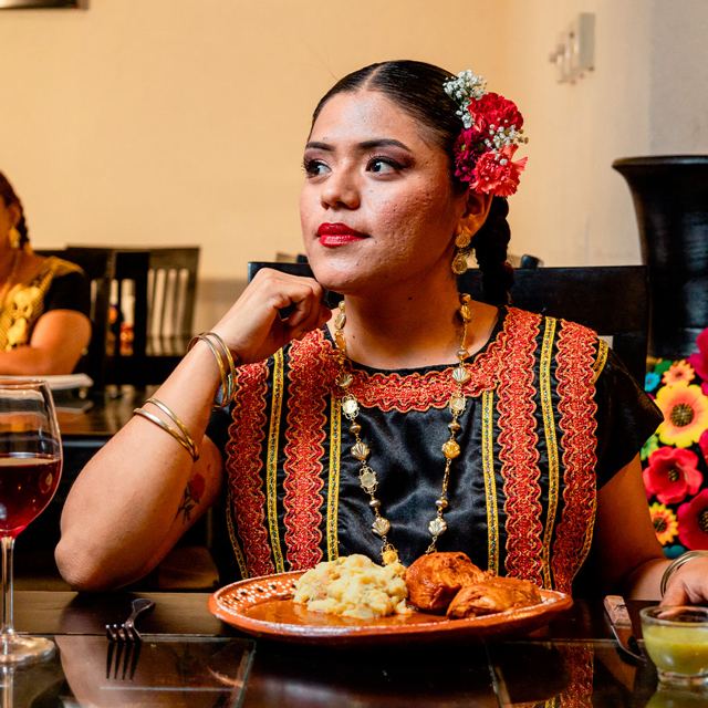 Comensal con traje regional y un plato de barro con su comida